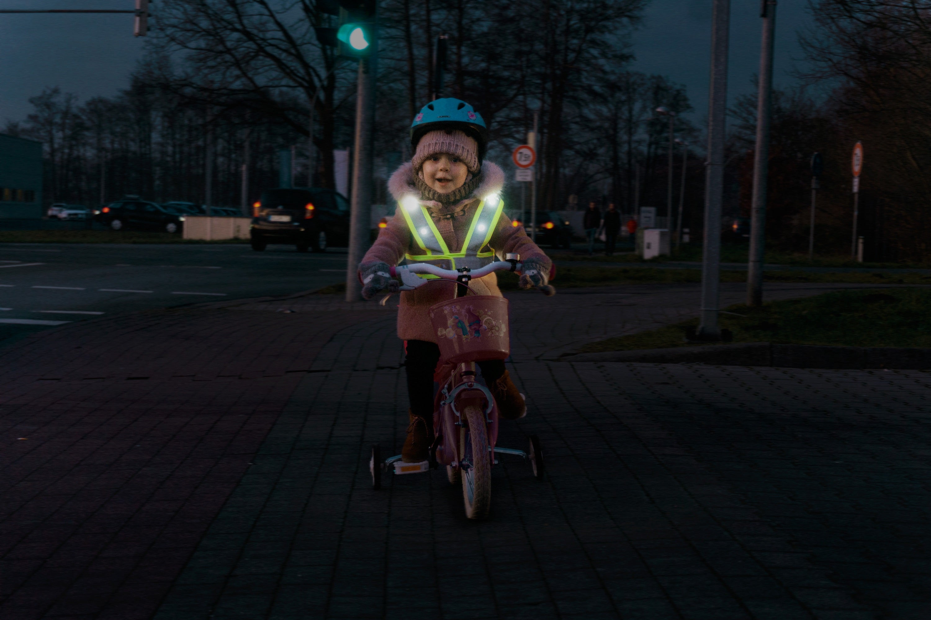 Kind auf dem Laufrad mit LED Warnweste für Kinder