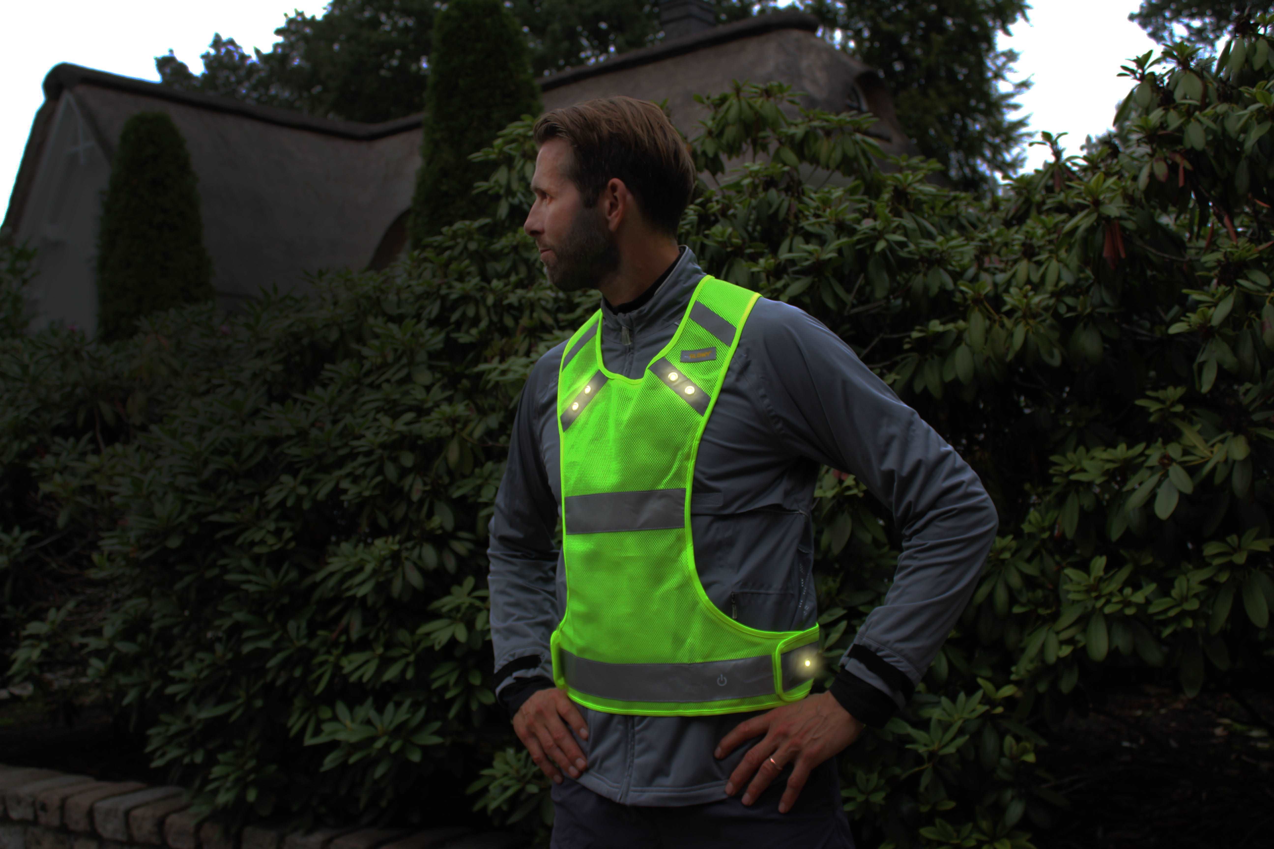 LED Sportweste am Mann mit leuchtenden LEDs – Bäume und Haus im Hintergrund